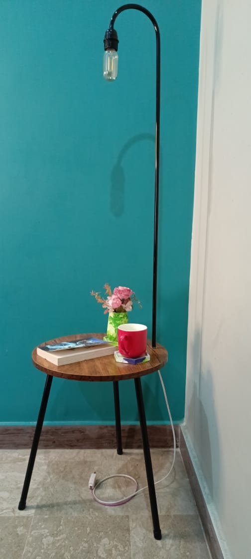 Fancy floor lamp glowing in dim lighting with functional side table beside couch