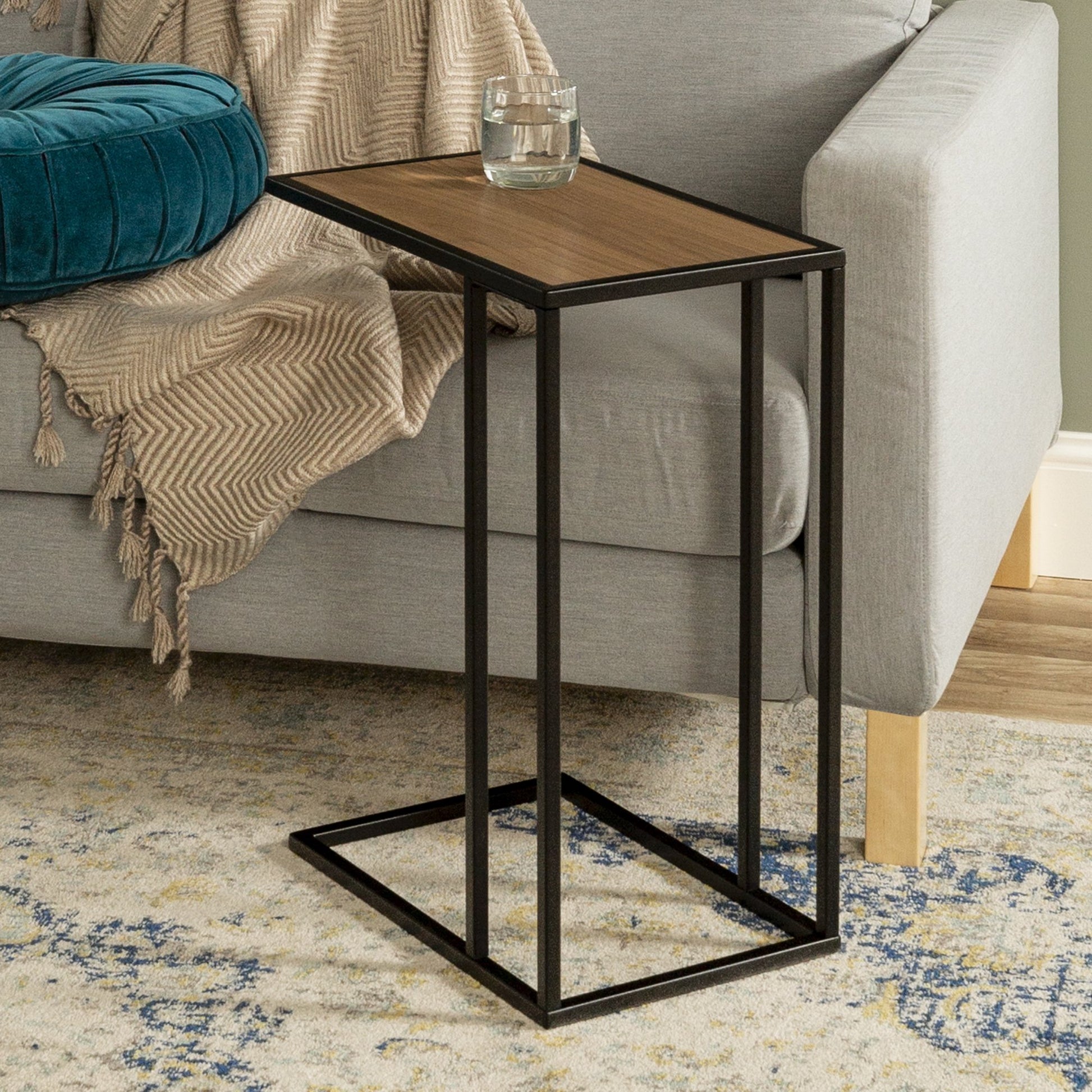 Modern C-shape side table with black steel frame and walnut top placed beside a sofa – MetalX