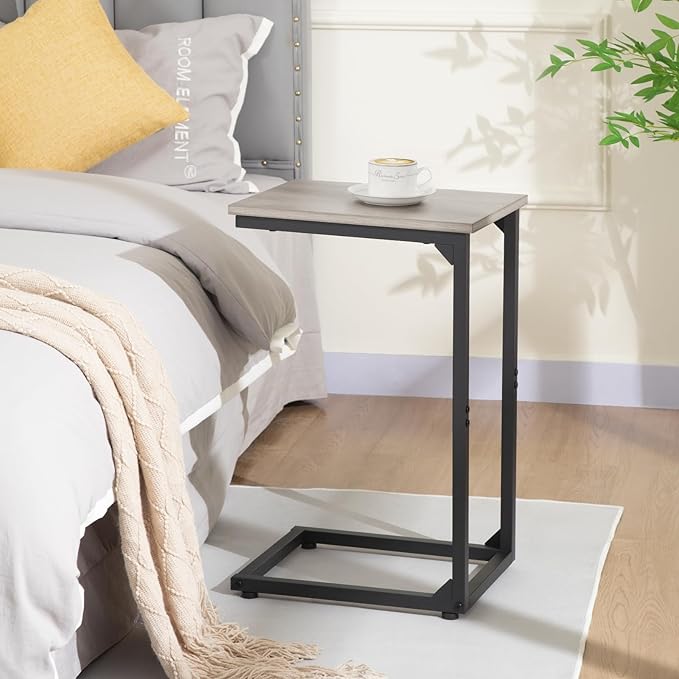 Small side table next to a bed with a cup on top, in a bedroom setting.
