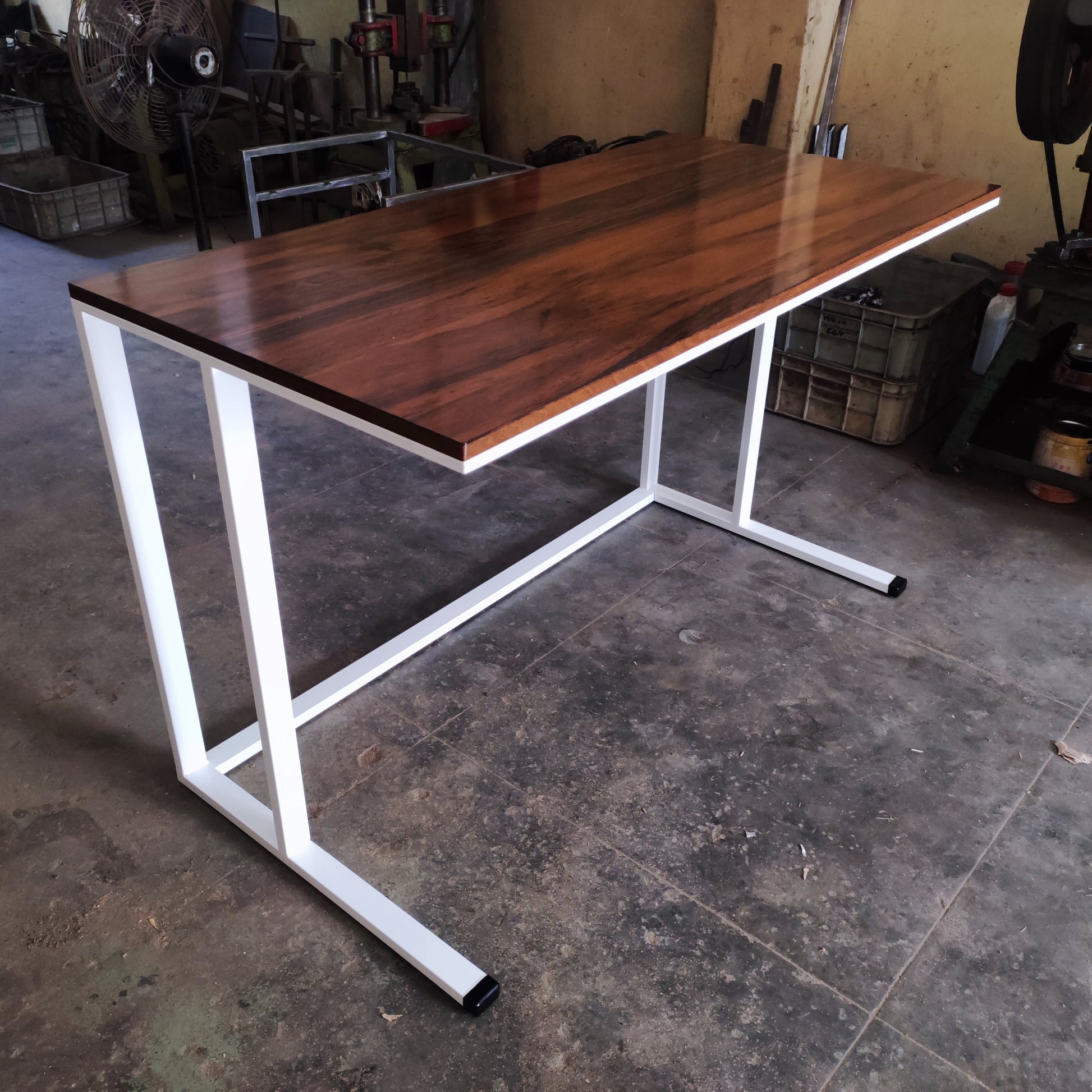 Wooden desk with white metal legs in a workshop setting