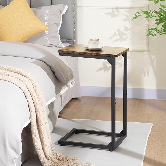 Wooden side table next to a bed with a cup on top, in a bedroom setting.